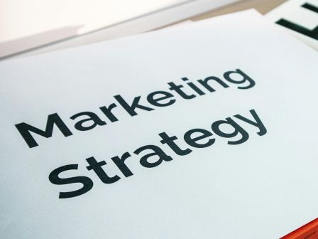 The image shows a document titled "Marketing Strategy," placed on a desk with part of another paper visible.